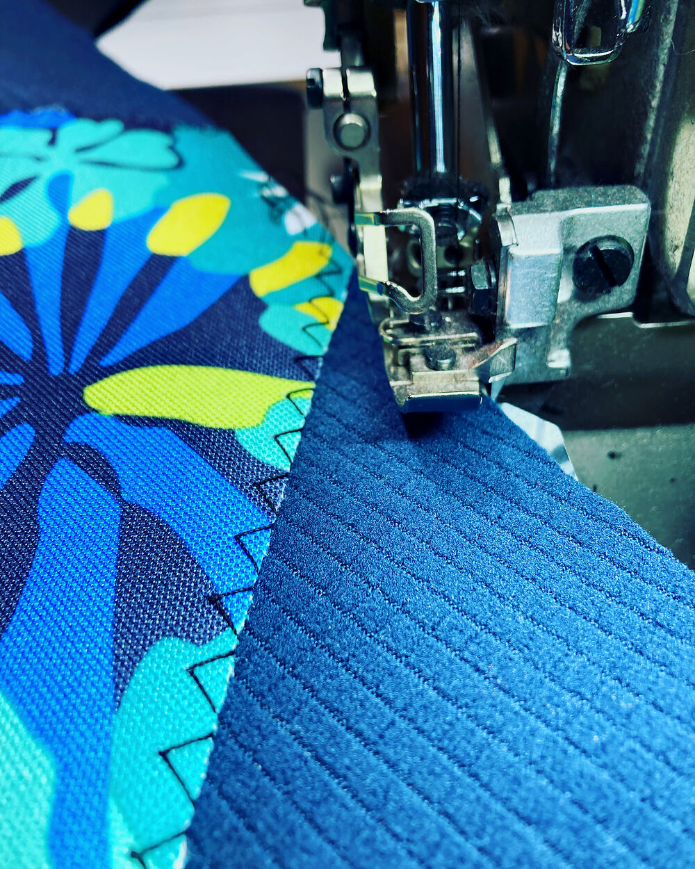 Sewing a blue floral print onto blue grid fleece