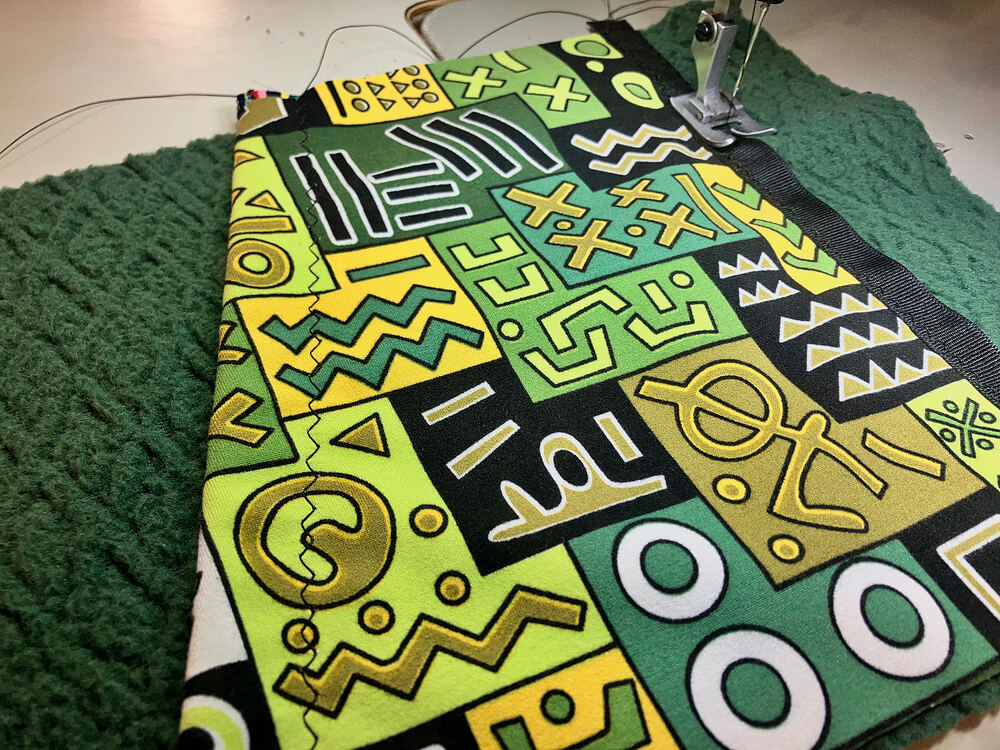 Sewing a green geometric print panel onto green fleece