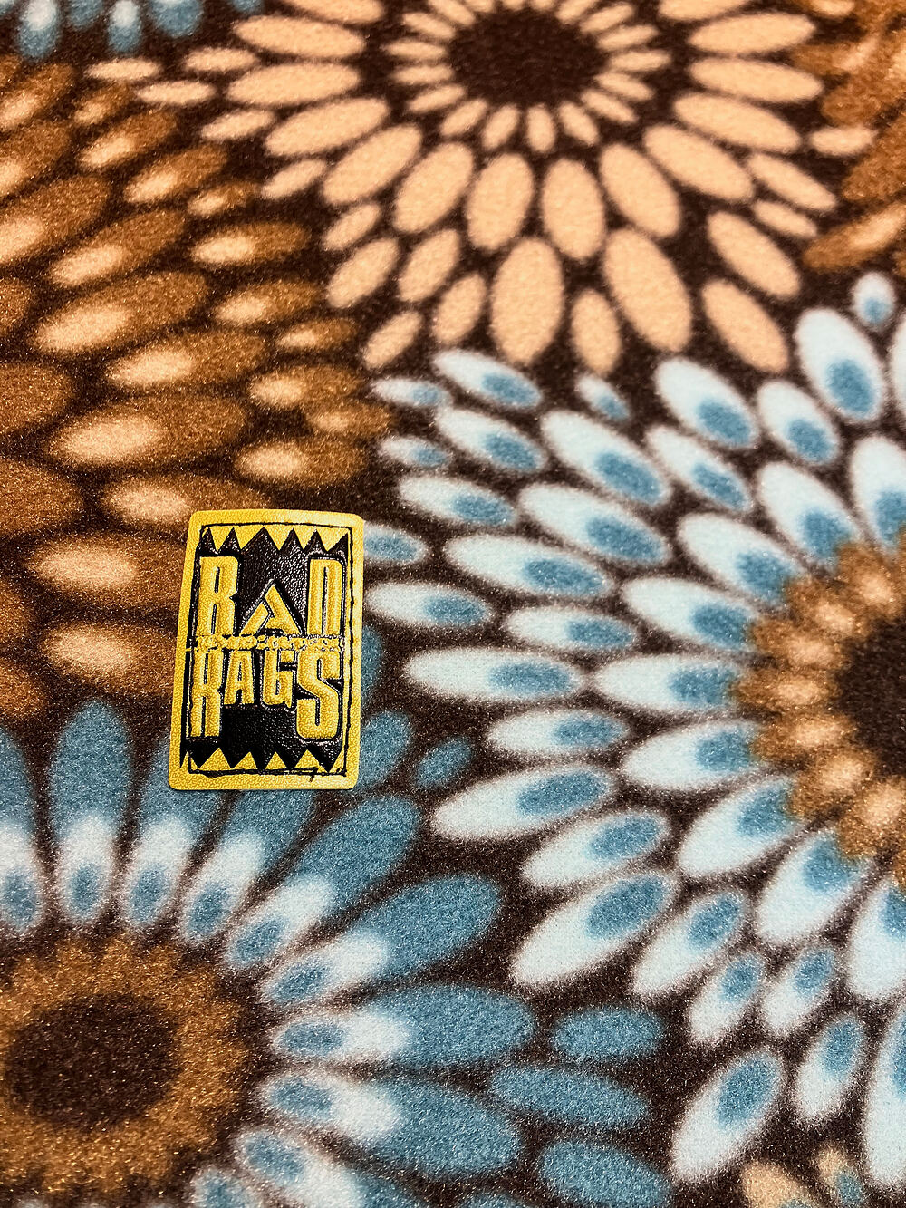 A gold Rad Rags label on sunflower-print fleece