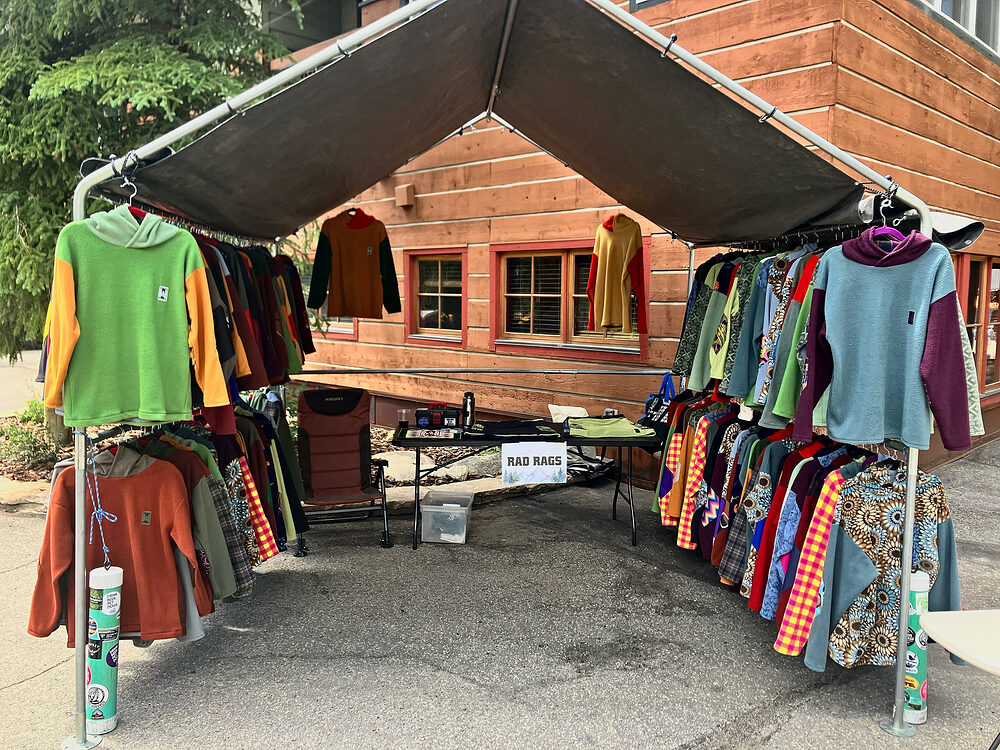 Rad Rags pop-up tent with racks of fleece outside a wooden building