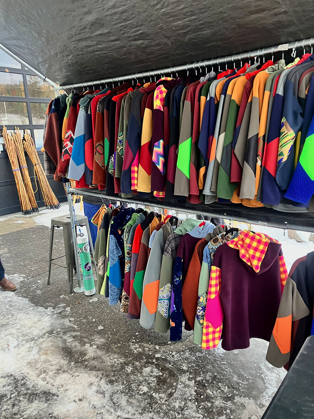 Rad Rags pop-up rack full of colorful fleece under a tent, with snow on the ground
