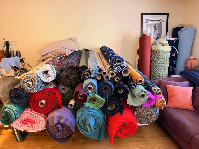A big pile of fleece rolls in every color, with bolts of fabric and a framed Breckenridge poster behind