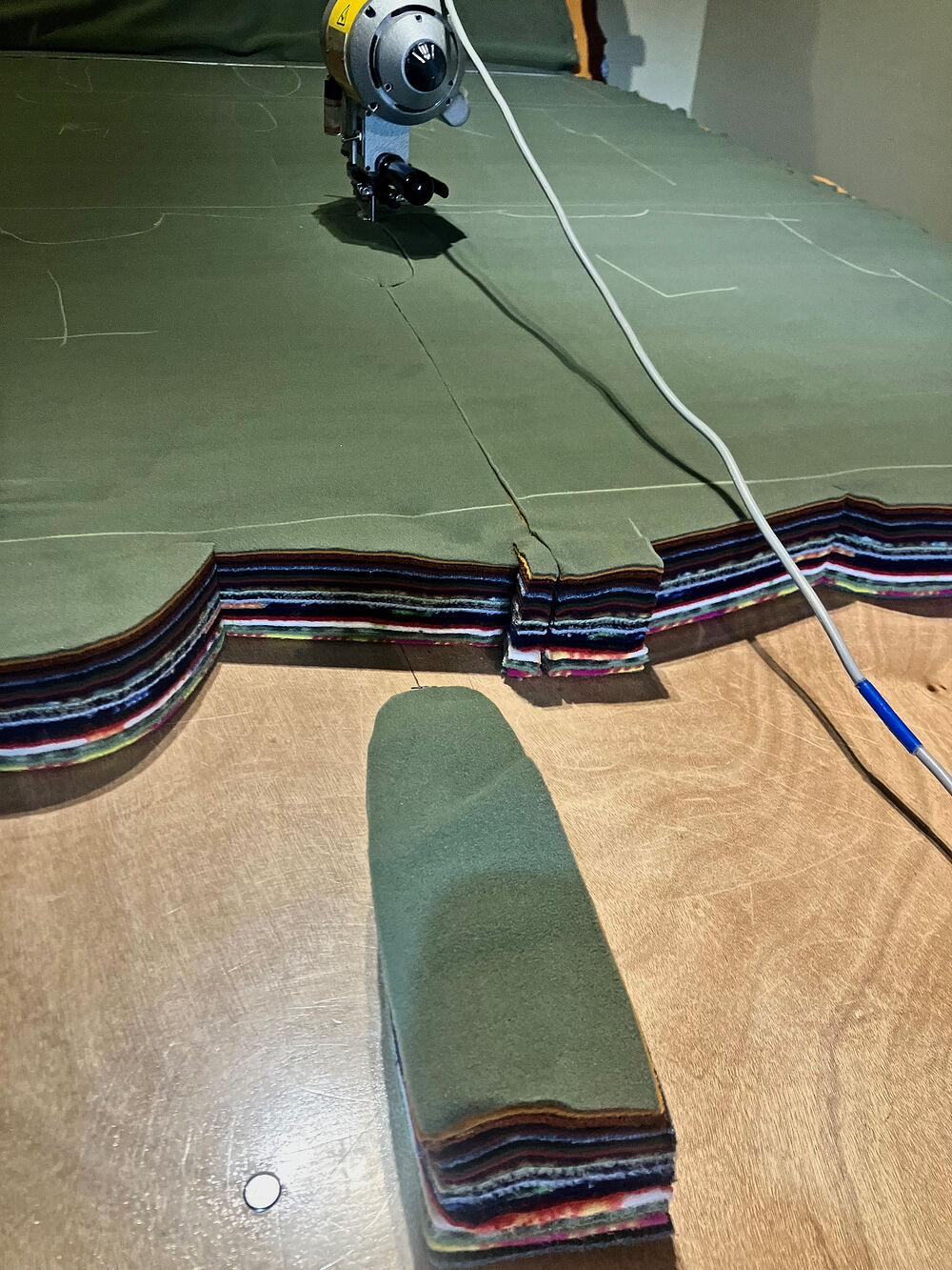 Electric cutter slicing through a tall stack of fleece layers