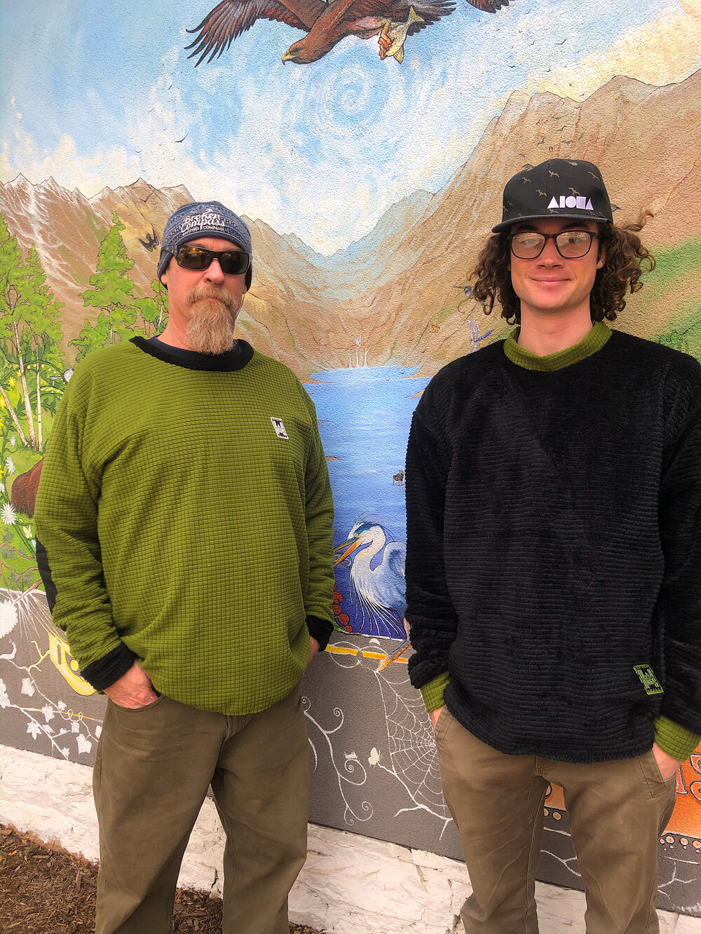 Two guys in Rad Rags crewnecks in front of a painted mountain mural
