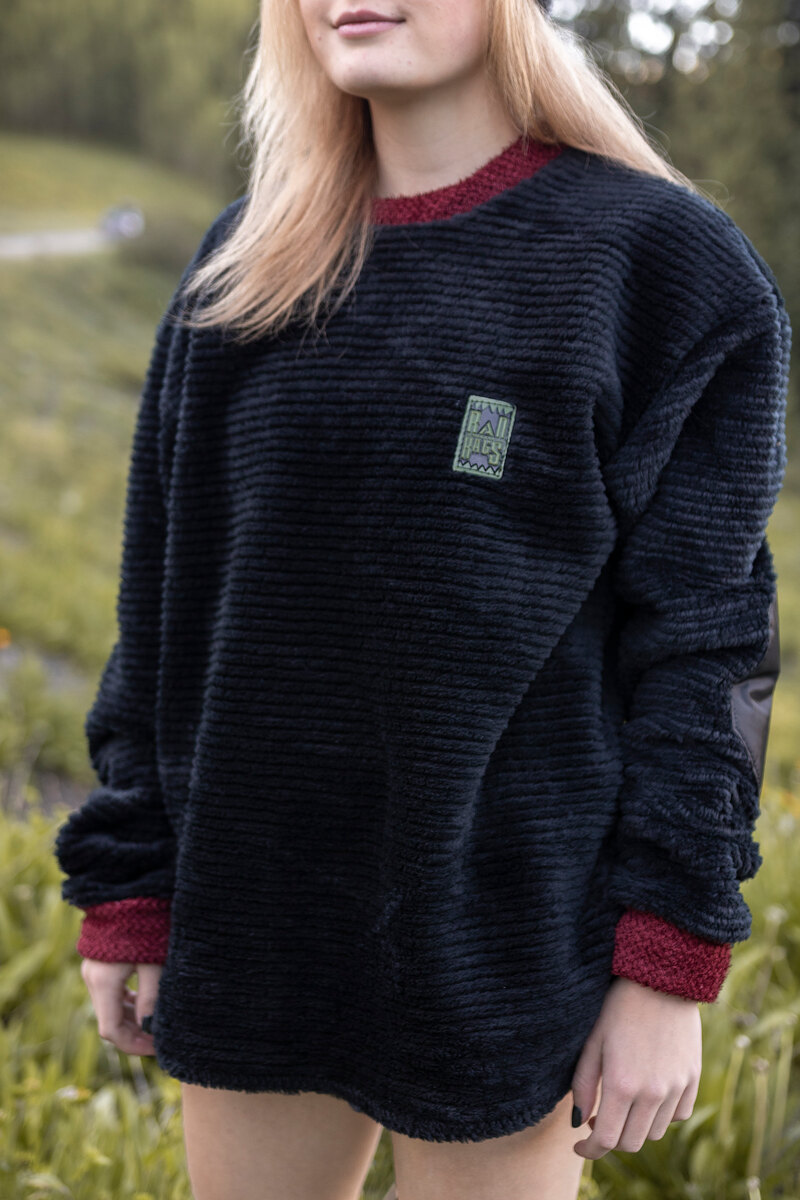 Model in a black textured fleece crewneck with maroon cuffs