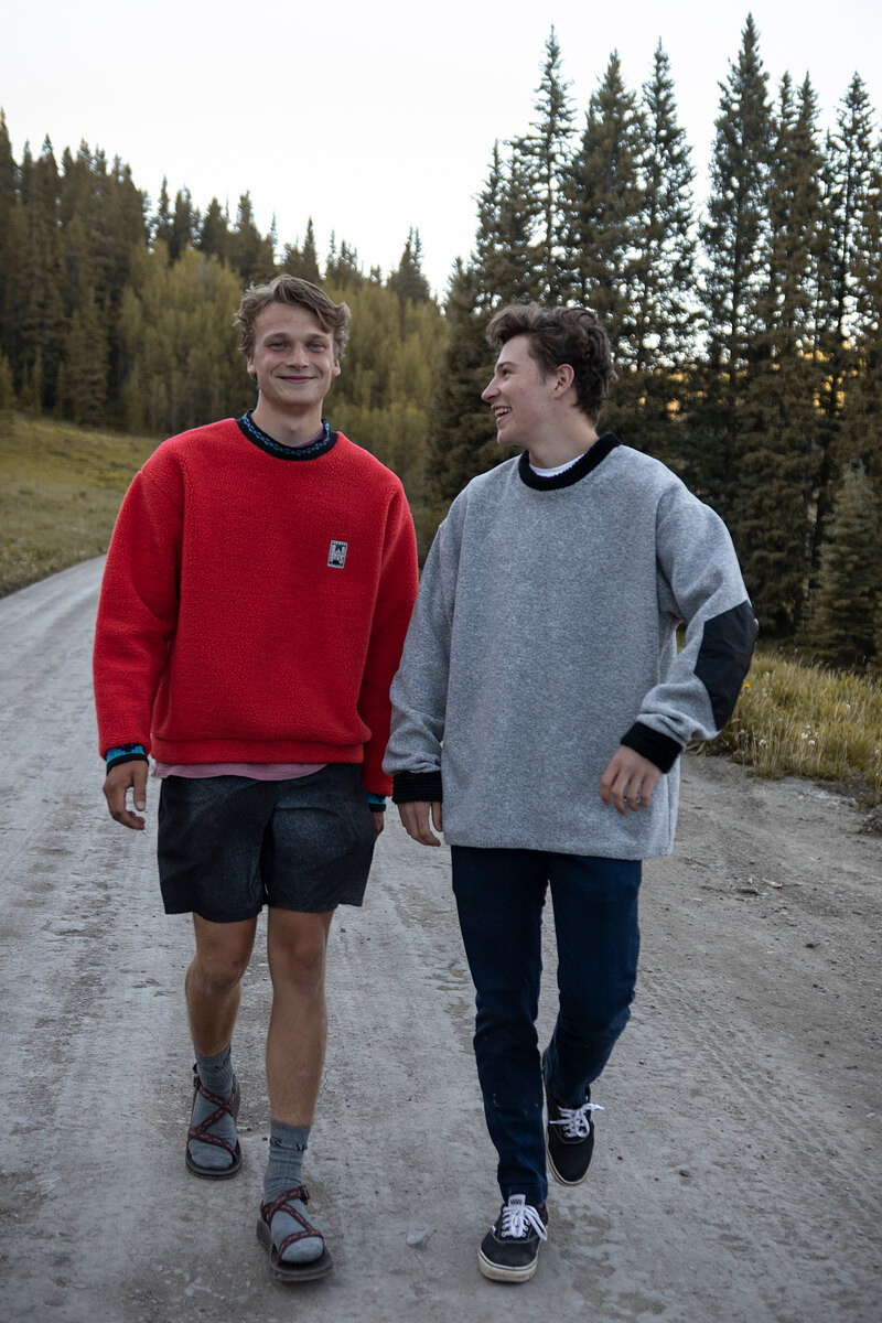 Two friends walking a dirt road in red and gray crewnecks