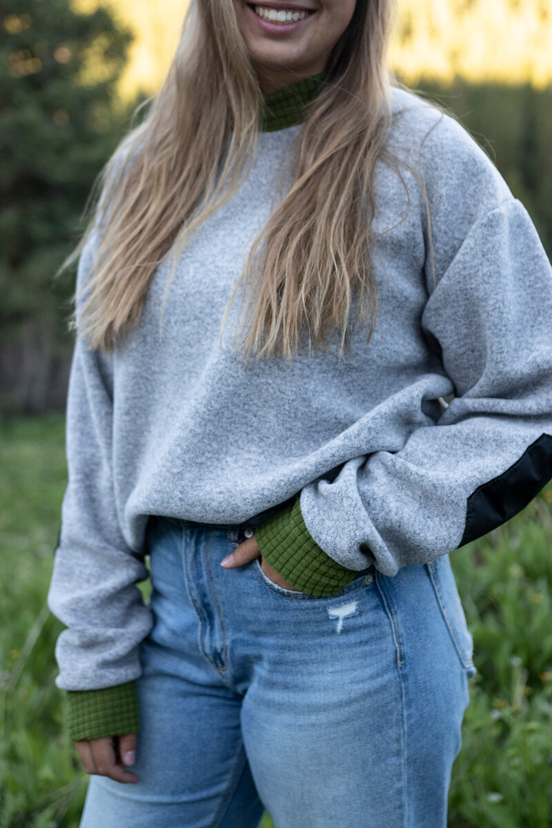 Smiling model in a heather gray crewneck with green cuffs