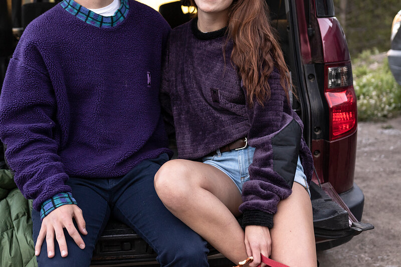 Two friends in purple fleece sitting on a truck tailgate