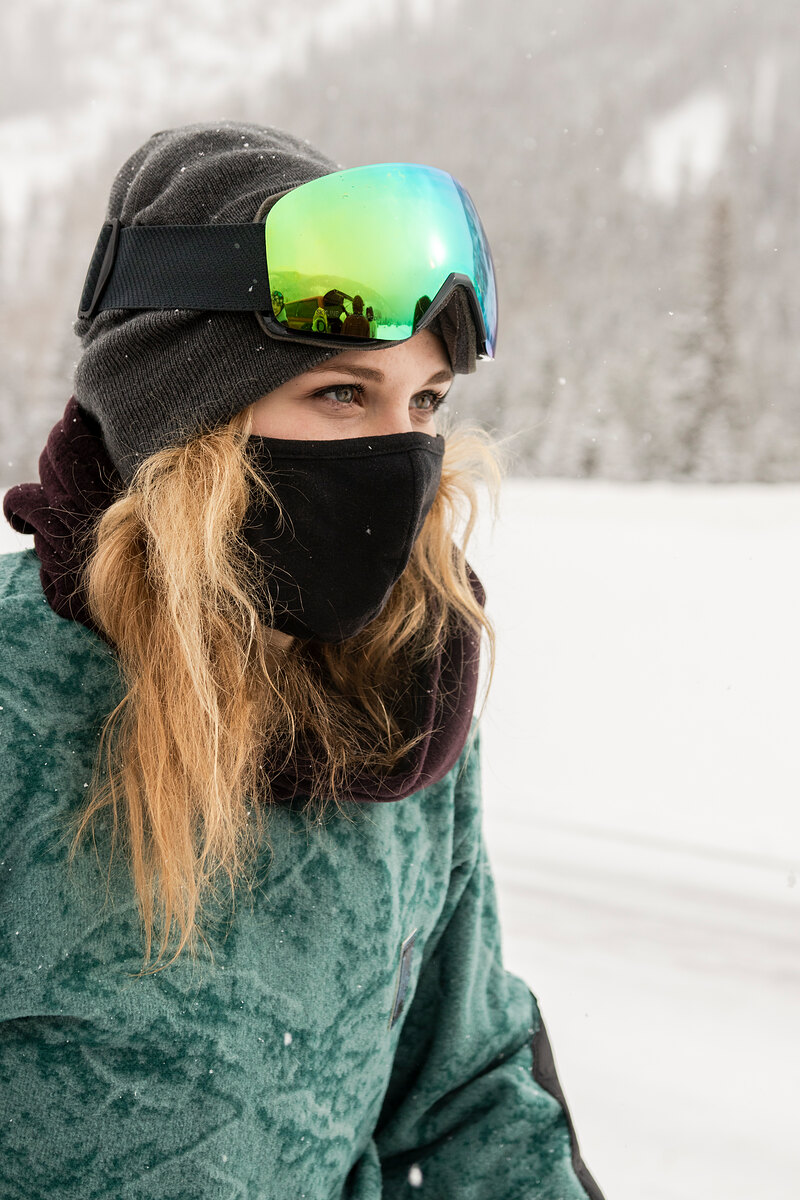 Model in a green print fleece with goggles and a face mask