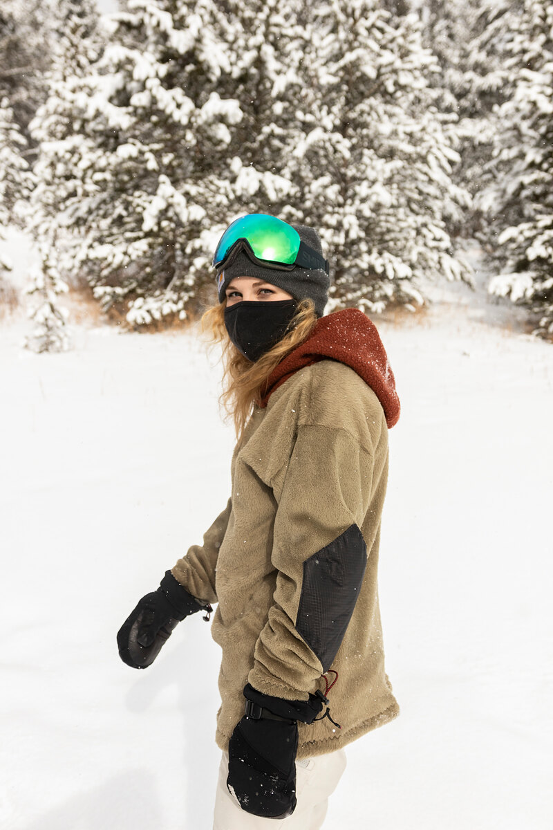 Model in an olive fleece with a maroon hood in the snow