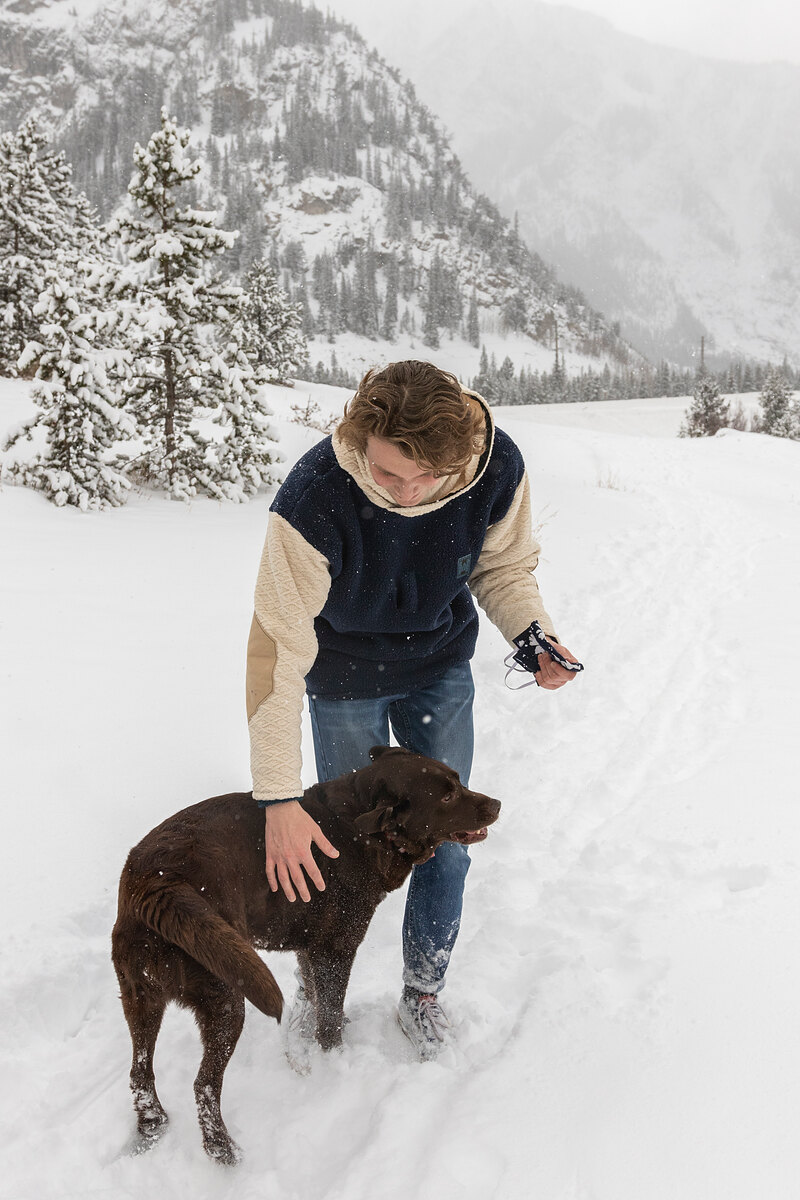 Model in a navy and cream fleece petting a chocolate lab