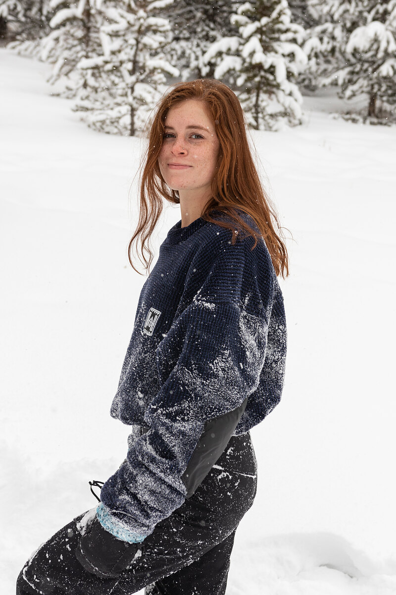 Model in a snow-dusted navy fleece looking back over a shoulder