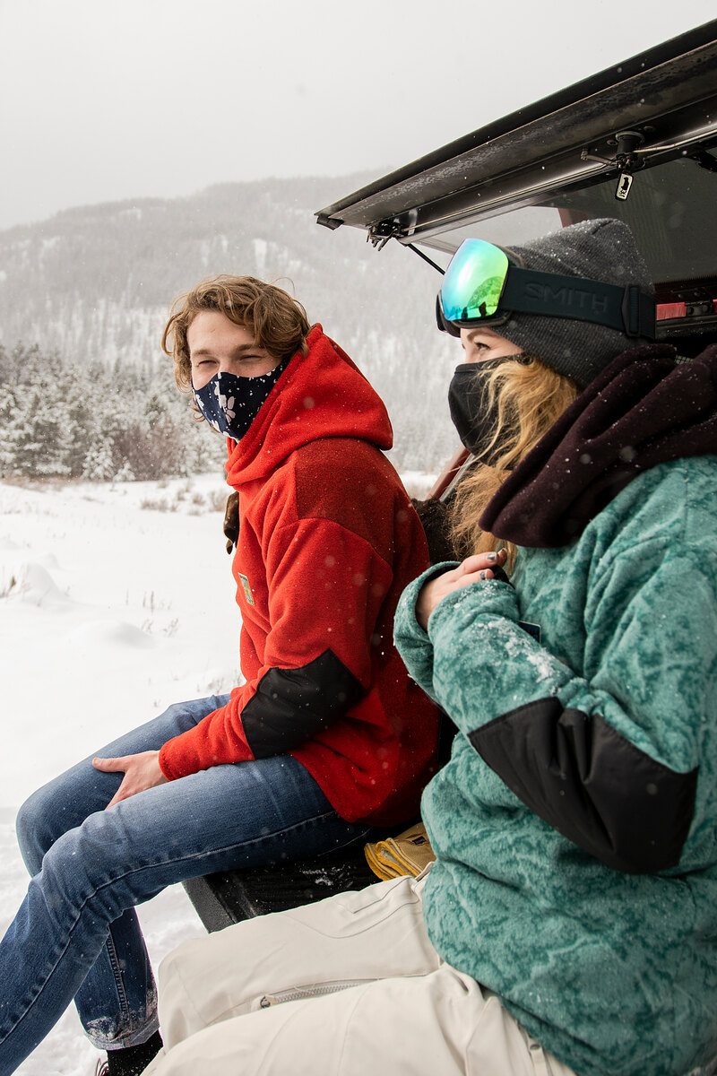 Friends in red and green fleece on a truck tailgate in the snow